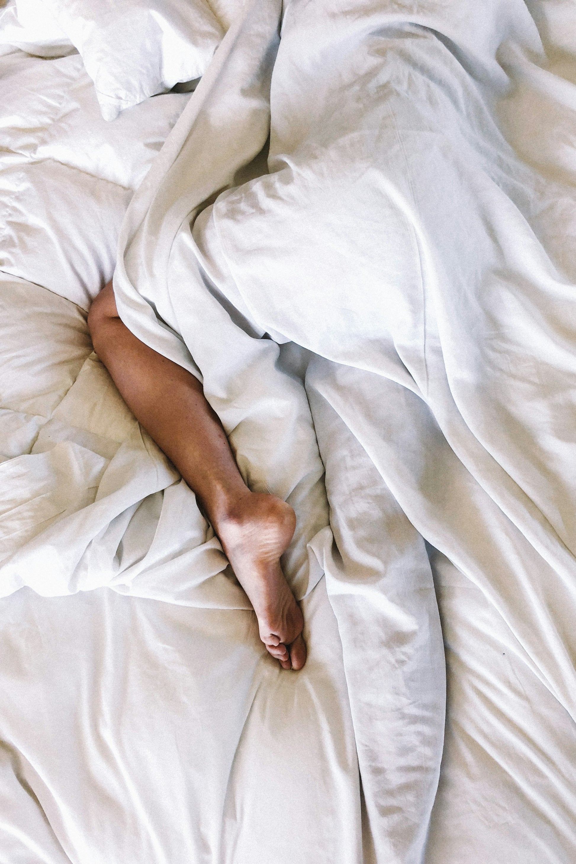 Vrouw slaapt onder wit beddengoed — Ralune slaapelixer werking